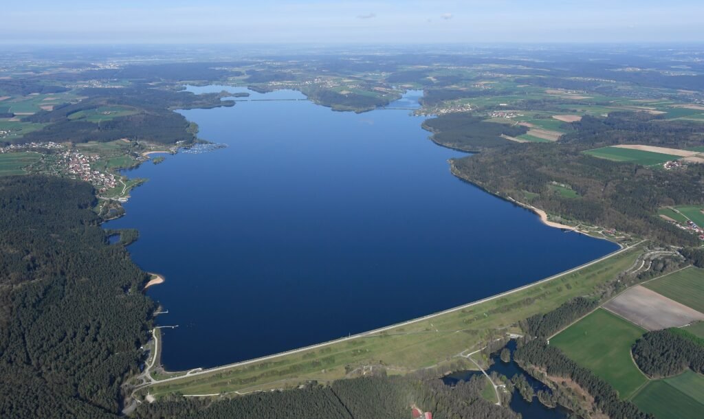 Luftbild des Großen Brombachsees mit Staudamm, umgeben von Wäldern und Feldern