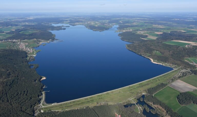Luftbild des Großen Brombachsees mit Staudamm, umgeben von Wäldern und Feldern